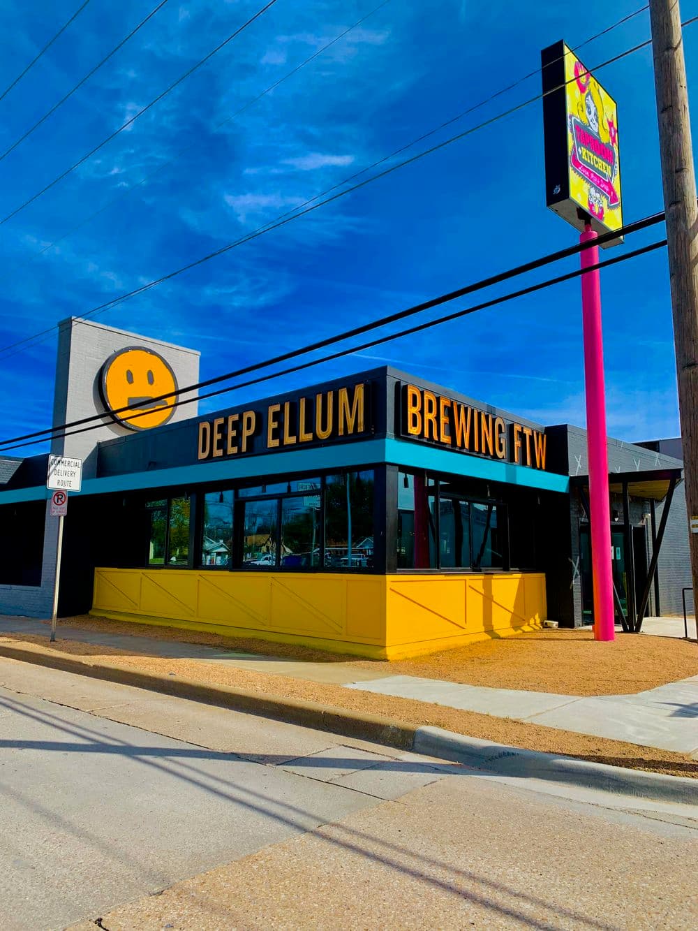 Deep Ellum Brewing building with yellow accents and sign against a blue sky.